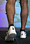 Beine einer Person mit weißen Sportschuhen und schwarzen Socken beim Gehen auf einem Laufband mit Markierungskugeln an den Waden.